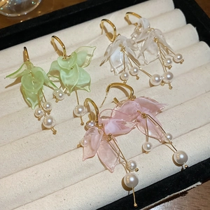 Detail view of floral tassel earrings with acrylic petals and pearls in three colors