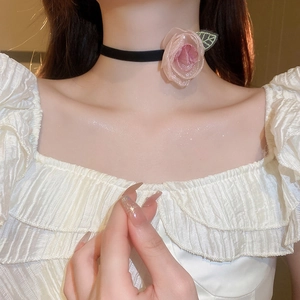 Detail of a black choker necklace with a pink fabric rose and a green leaf embellishment
