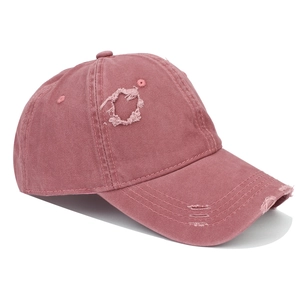 Close-up of distressed pink cotton baseball cap featuring vintage washed fabric and ripped details