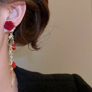 Detail von roten Rosen-Ohrringen mit Perlen an einem Modell für einen eleganten Look