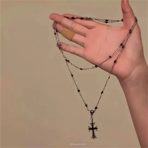 Détail macro d'un pendentif croix argentée rétro gothique avec chaîne à billes noires