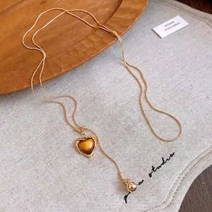 Golden Y-shaped snake chain necklace featuring a heart-shaped amber resin pendant