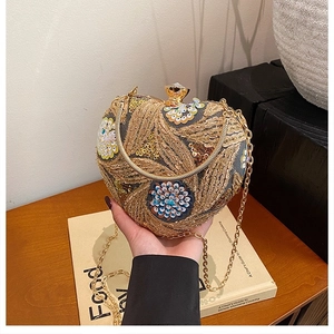 Detail of heart-shaped clutch bag with golden embroidery, sequins and metal handle