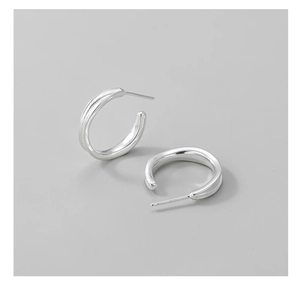 Macro shot of silver S925 sterling silver C-shaped hoop earrings on grey background