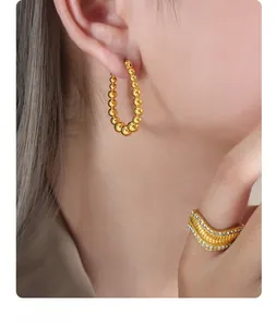Dettaglio di orecchini a cerchio con perle in oro 18K e anello a fascia strutturato