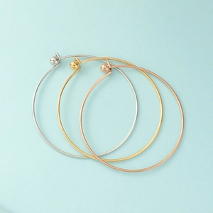 Three minimalist stainless steel bangles in silver, gold, and rose gold with screw beads
