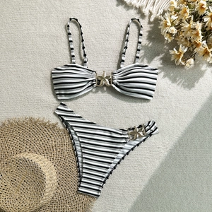 Detail of striped bikini set featuring nautical gold starfish buckles on a woven mat