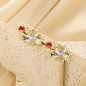 Macro view of gold heart earrings with red and white crystals on textured stone