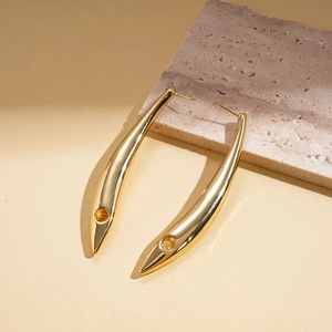 Détail de boucles d'oreilles courbées plaquées or 18 carats avec finition miroir polie