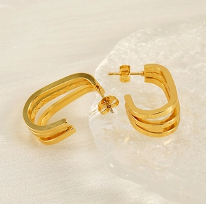 Detail of gold multilayer U-shaped earrings with textured diamond pattern finish
