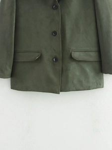 Detail of dark green suede blazer featuring classic flap pockets and three-button closure