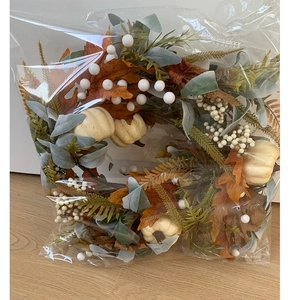Detail of fall garland in packaging featuring white pumpkins and artificial autumn leaves