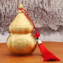 Close-up of brass gourd with red tassel and dragon engravings on wooden background