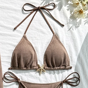 Close-up of waffle-knit bikini fabric featuring a decorative golden starfish metal buckle