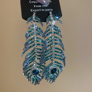 Detailed macro of luxury leaf feather earrings with gradient blue and green rhinestones