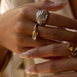 Close-up of model wearing a two-tone silver and gold twisted cable ring with knot design