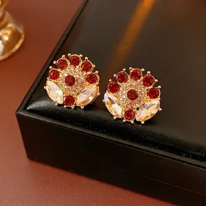 Vintage gold-plated floral earrings with red and clear crystals on a black leather box