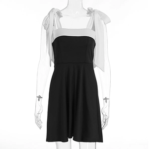 Detail of white satin bow shoulder straps on a black and white A-line summer dress