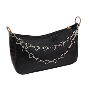 Detailed view of crocodile pattern texture and decorative heart-shaped metal chains on bag