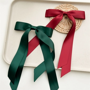 Detail of elegant double-layered satin bow hair clips in dark green and burgundy red