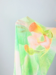 Detail of sheer mesh fabric with orange and green floral print showing high transparency