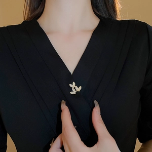 Detail of three gold butterfly brooches with shell texture and crystals on a black outfit