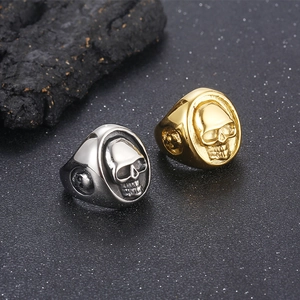 Detailed view of punk skull rings in gold and silver finishes on dark rock texture