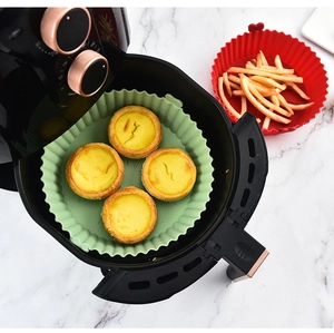 Dual-color silicone air fryer liners with egg tarts and french fries on marble surface