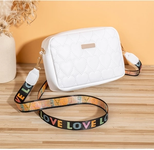 Detail of white heart-quilted crossbody bag with colorful LOVE embroidered wide strap