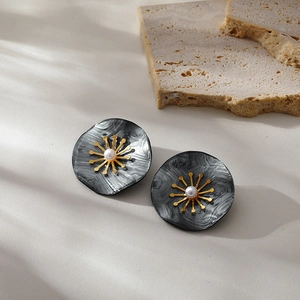 Close-up of gold flower stud earring with grey marble texture and center white pearl