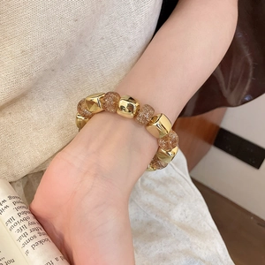 Close-up of geometric acrylic beaded bracelet with gold cubes and amber glitter beads