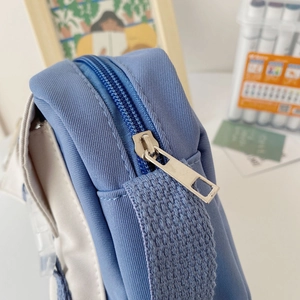 Detailed close-up of blue and white nylon bag showing sturdy metal zipper and woven handle