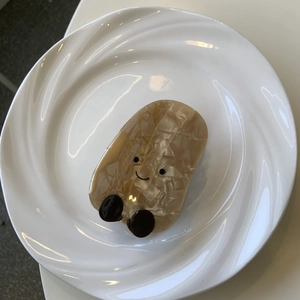 Dettaglio della molletta per capelli in acetato beige marmorizzato con faccina sorridente