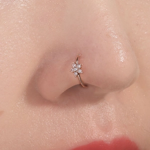 Close-up of a rose gold flower nose ring with sparkling crystals on a model's nose