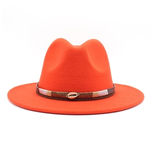Detail of orange wool fedora featuring a woven band and a gold shell accessory
