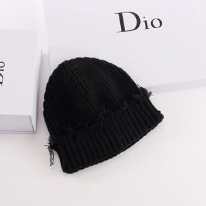 Detail of black ribbed knit beanie with frayed edges on a white background