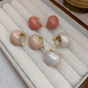 Detailed view of three pairs of retro C-shaped gold-plated earrings in various soft colors