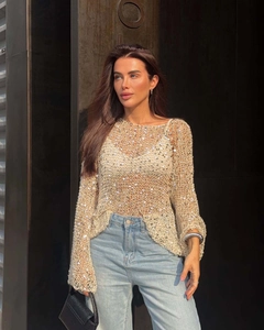 Detail of sequins on knit sweater with crochet texture and hollow design in golden beige