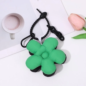 Green plush flower keychain with black center on a white table with magazine