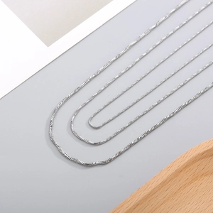 Polished silver stainless steel snake chain necklace displayed on a wooden stand