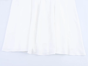 Close-up of the flowing white hemline with soft fabric pleats on a sweet princess dress