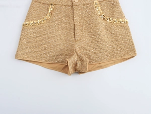 Detail of high-waisted gold tweed shorts with sequins and floral metal accents