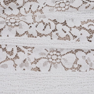 Macro shot of white floral lace fabric with nude lining and intricate mesh stitching