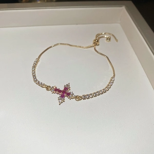 Makroansicht des goldenen Kreuzarmbands mit rosa Zirkonia und verstellbarem Zugverschluss