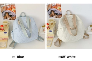 Dettaglio di zaini trapuntati in azzurro e bianco crema su una scrivania da studio