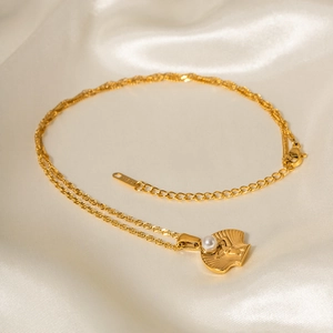 Detail of gold starfish shell necklace with pearl pendant on white silk fabric