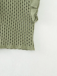 Détail d'un haut en tricot vert avec rayures ajourées et manches à volants froufrous