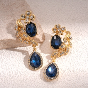Detailed macro of vintage gold earrings with deep blue gemstones and small white diamonds