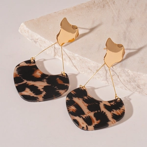 Détail de boucles d'oreilles dorées irrégulières avec pendentifs cœur motif léopard