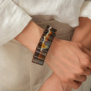 Detail of vintage acrylic marbled flower bangle on wrist with warm tones and textures